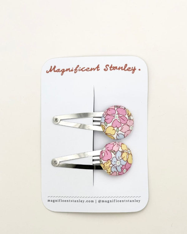 Pair of liberty sadie rose floral hair clips on a 'Magnificent Stanley' branded card.