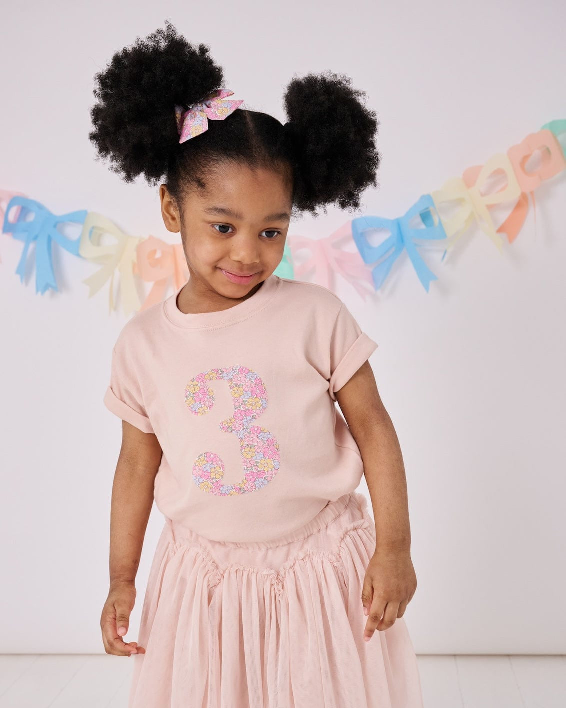 a 3 year old girl wearing a pink birthday t-shirt with a number 3 cut from sadie rose liberty floral print on the front