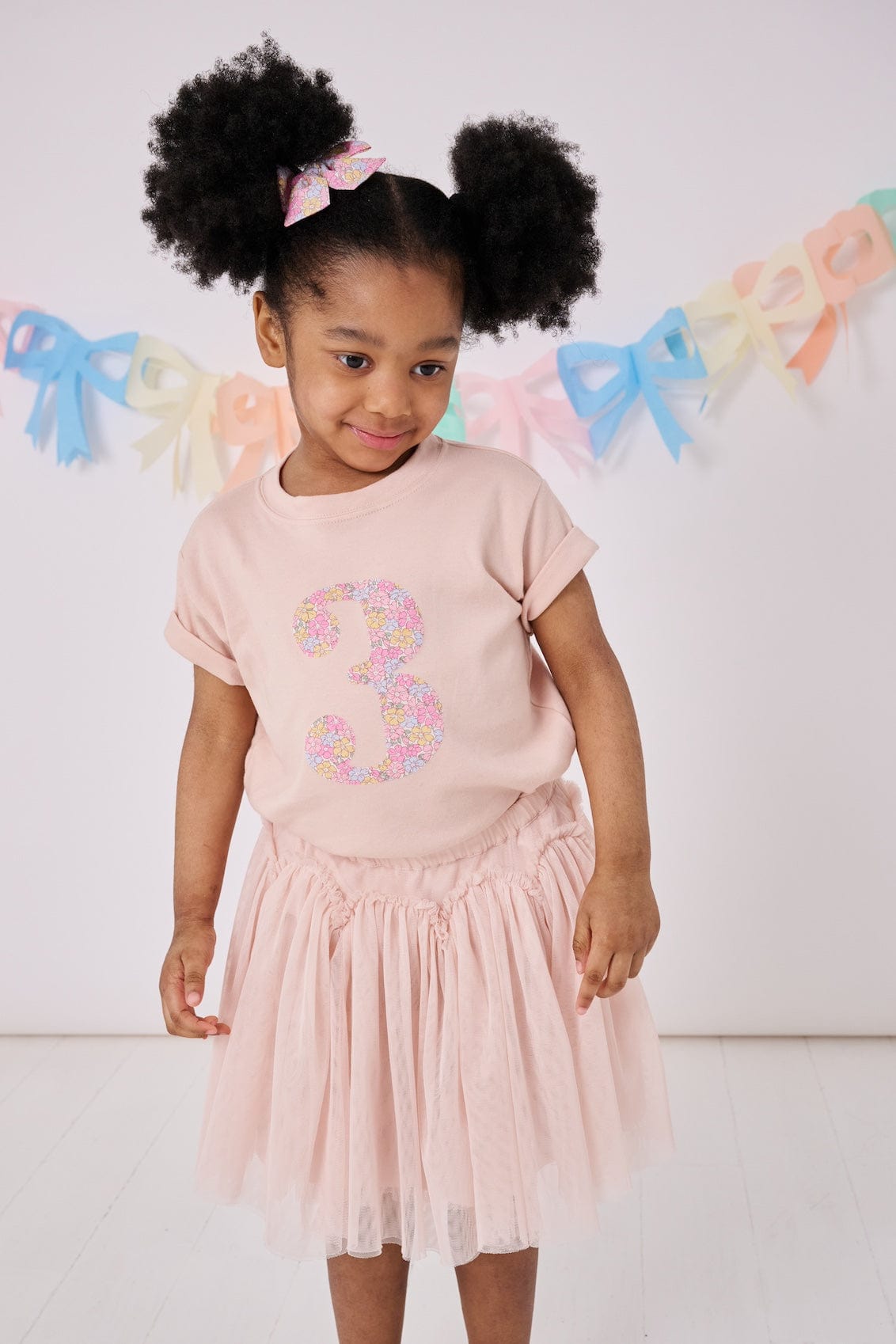 a 3 year old girl wearing a pink birthday t-shirt with a number 3 cut from sadie rose liberty floral print on the front