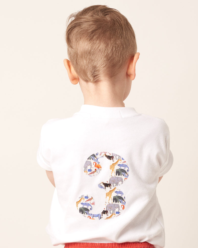 Child wearing a white t-shirt with a colourful number 3 design in zoo liberty print on the back.
