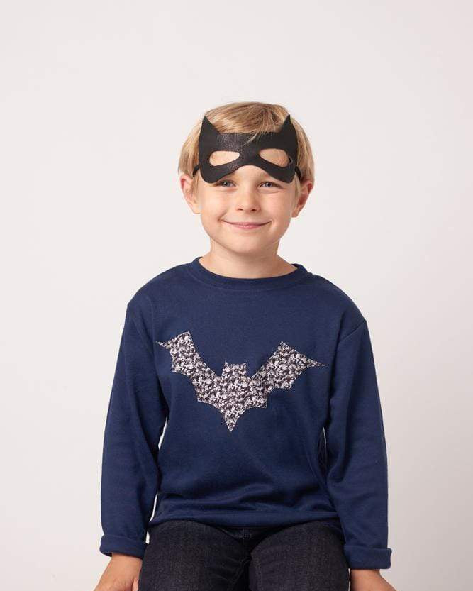 A boy in a navy cotton tee with a halloween bat on it made from Liberty Alba print fabric.