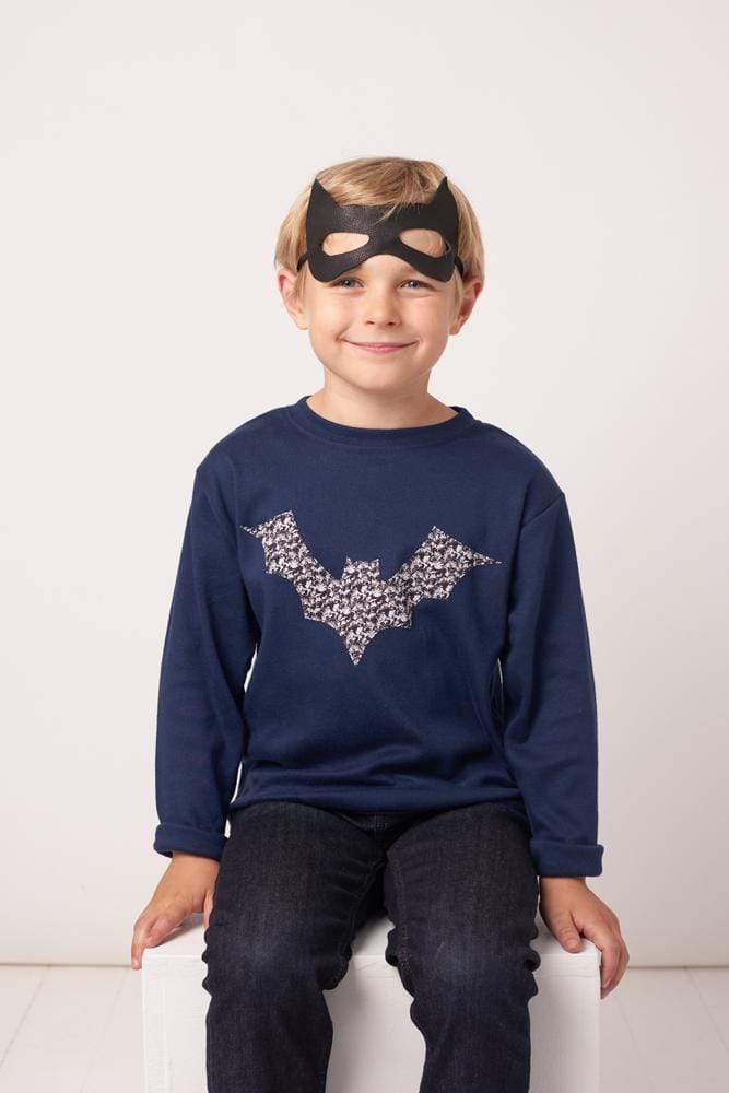 A boy in a navy cotton tee with a halloween bat on it made from Liberty Alba print fabric.