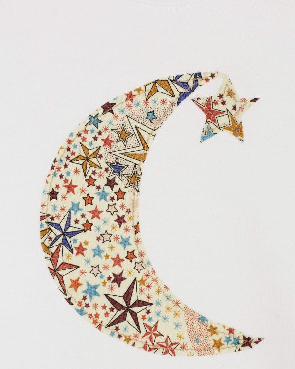 A white cotton babygrow with a moon and hanging star sewn on the front, cut from Adelajda starry Liberty print. a close up of the stitching.