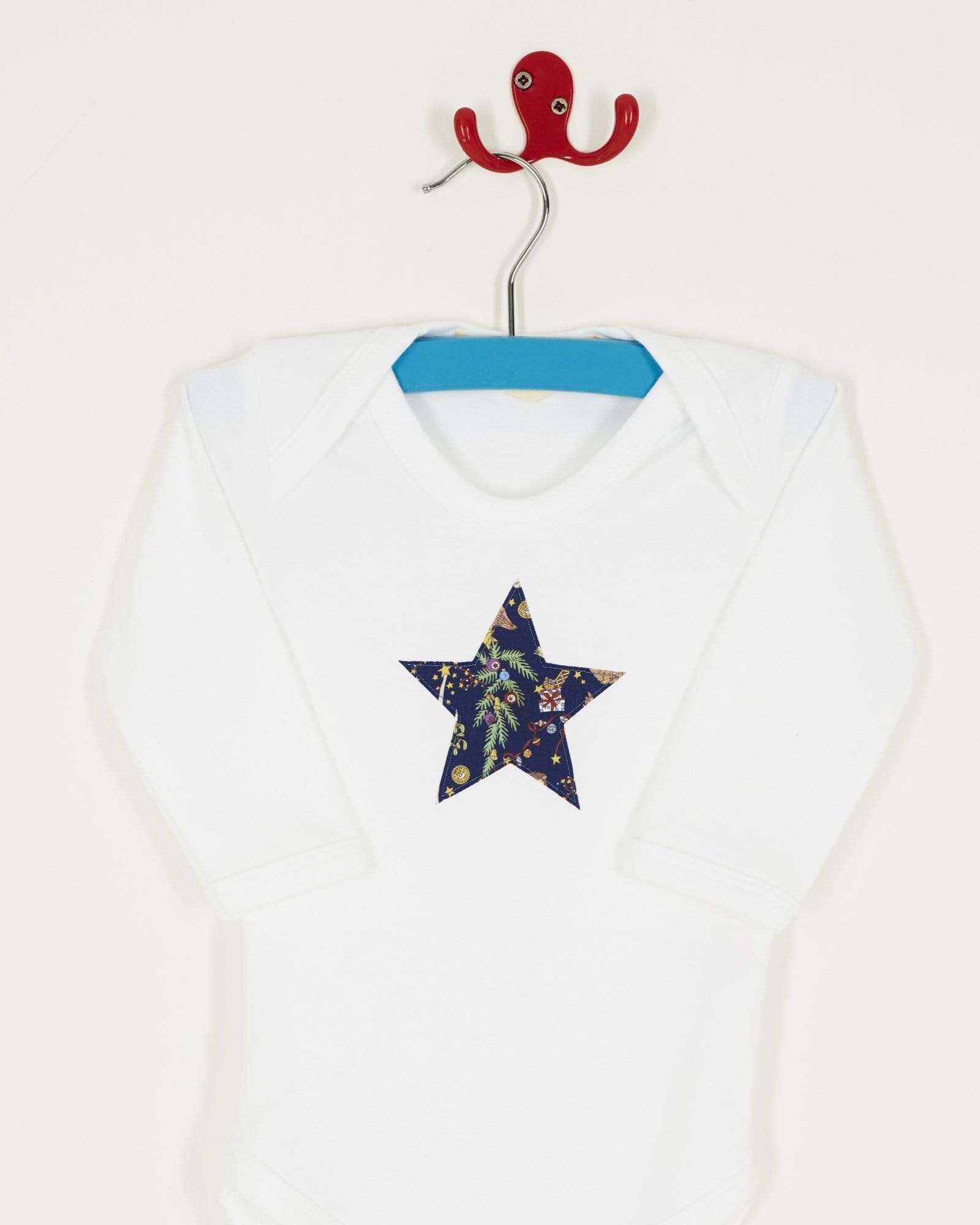 A white bodysuit babygrow with a Liberty Christmas print festive star sewn on the front.