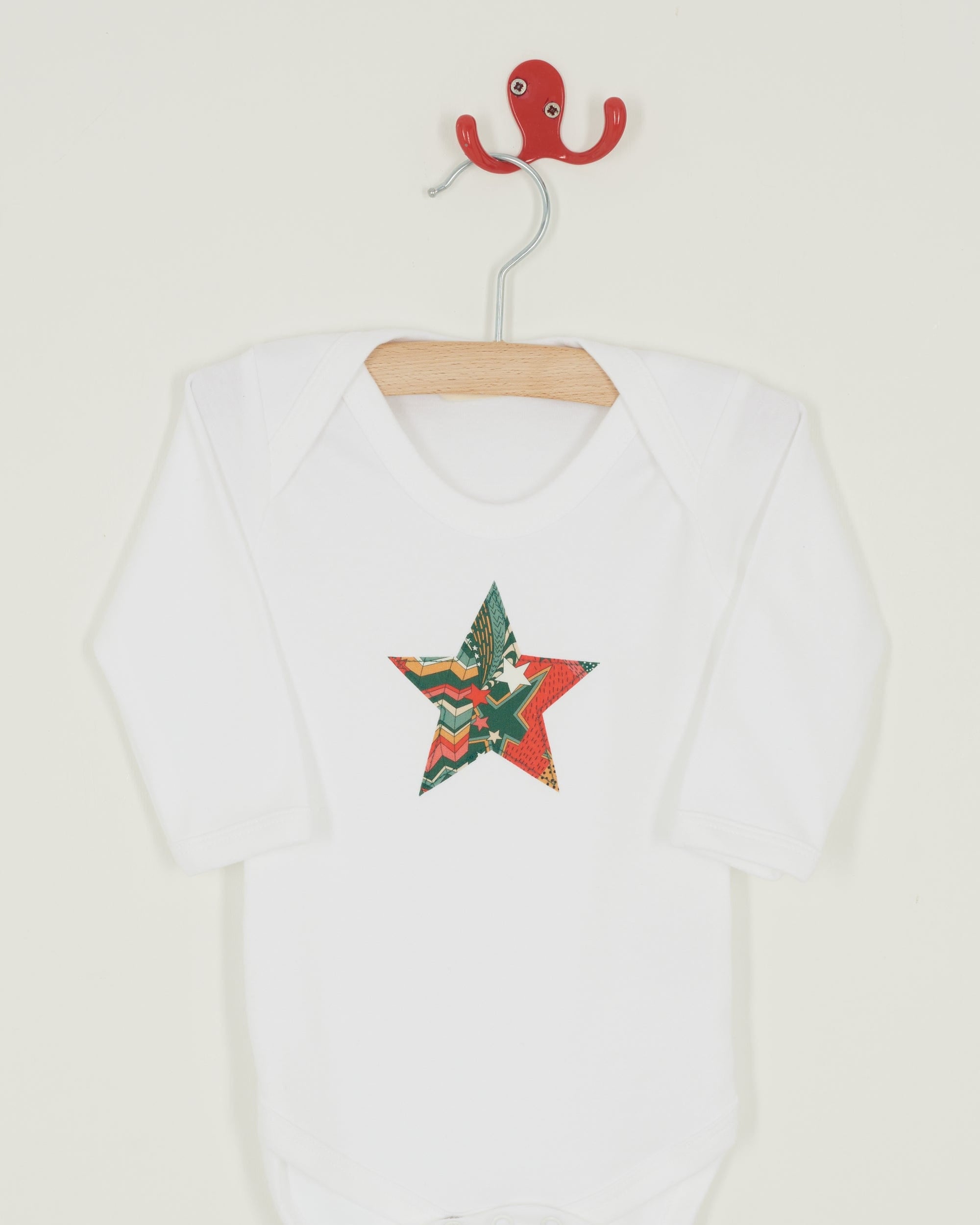 A white bodysuit babygrow with a Liberty My Little Star print festive star sewn on the front.