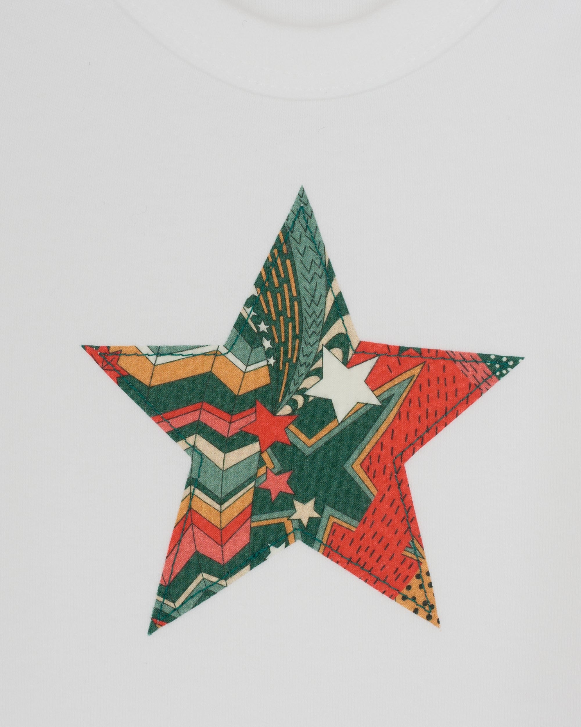A close up of a white bodysuit babygrow with a Christmas Liberty My Little Star print festive star sewn on the front.