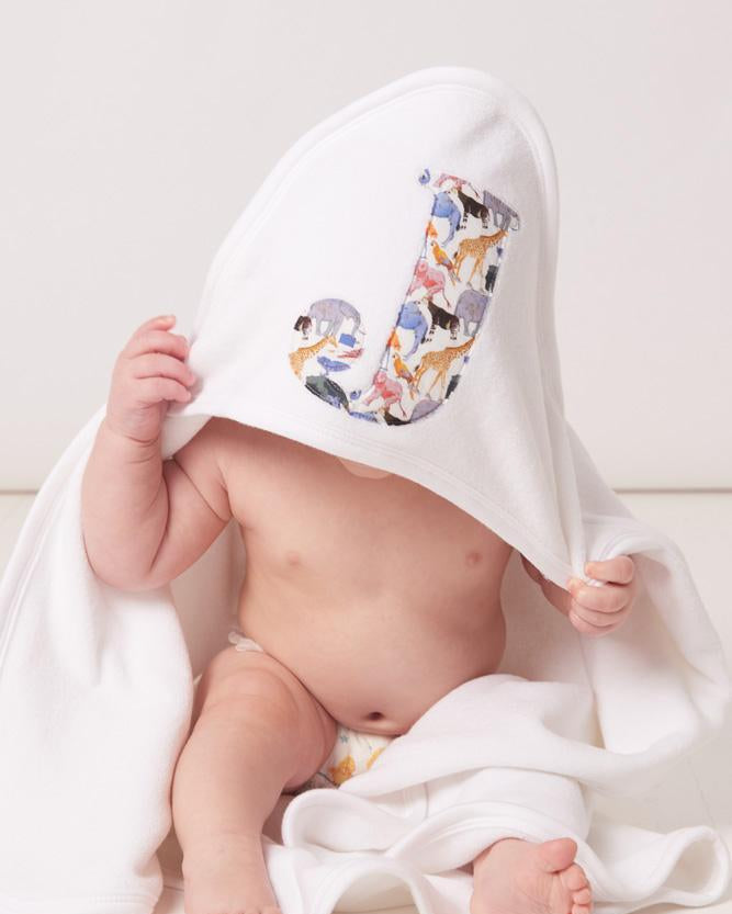 A little baby wearing a soft cotton hooded baby towel with his initial sewn on the hood in queue for the zoo liberty print