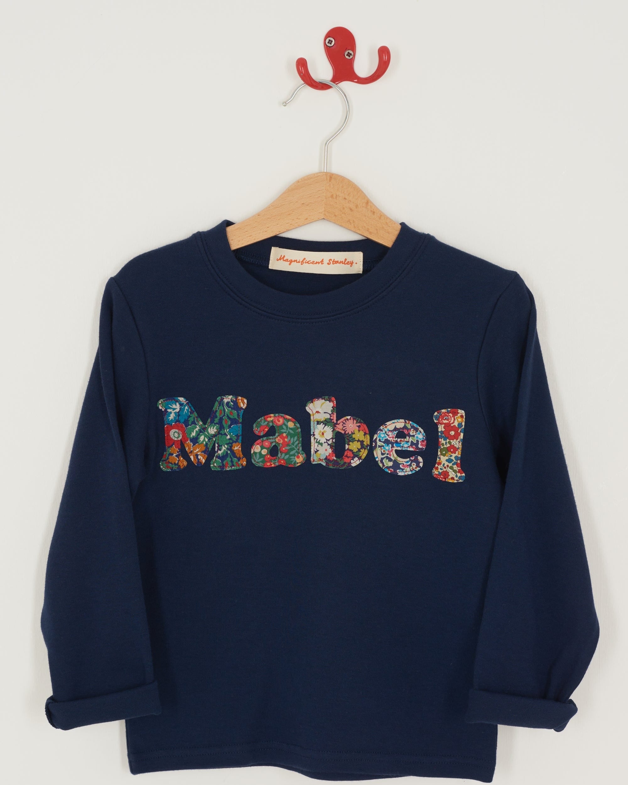 A navy t-shirt with the name mabel  sewn on in mixed Liberty print lowercase letters.