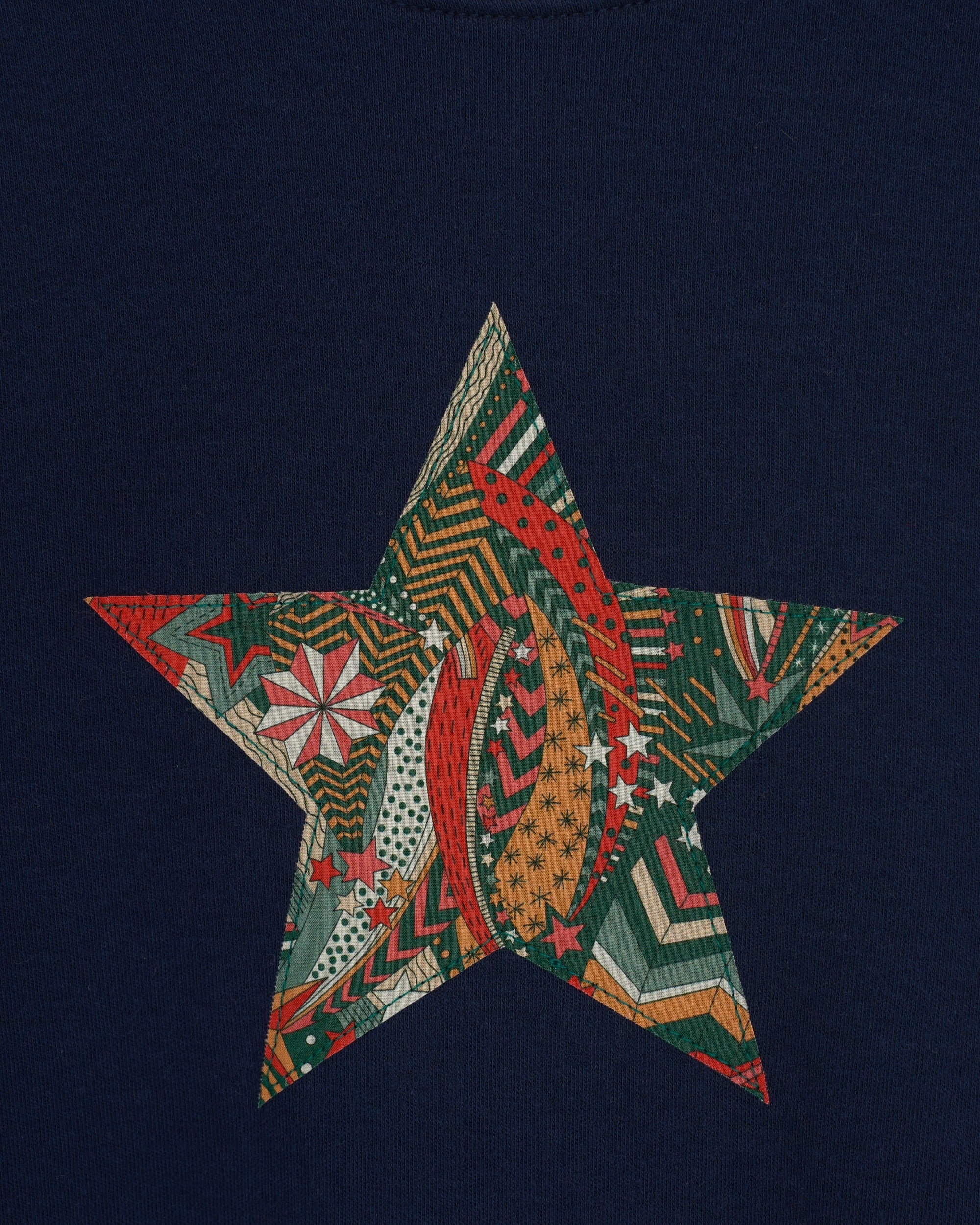 A navy long sleeve christmas t-shirt with a festive star on the front made from Liberty My Little Star print on the front.