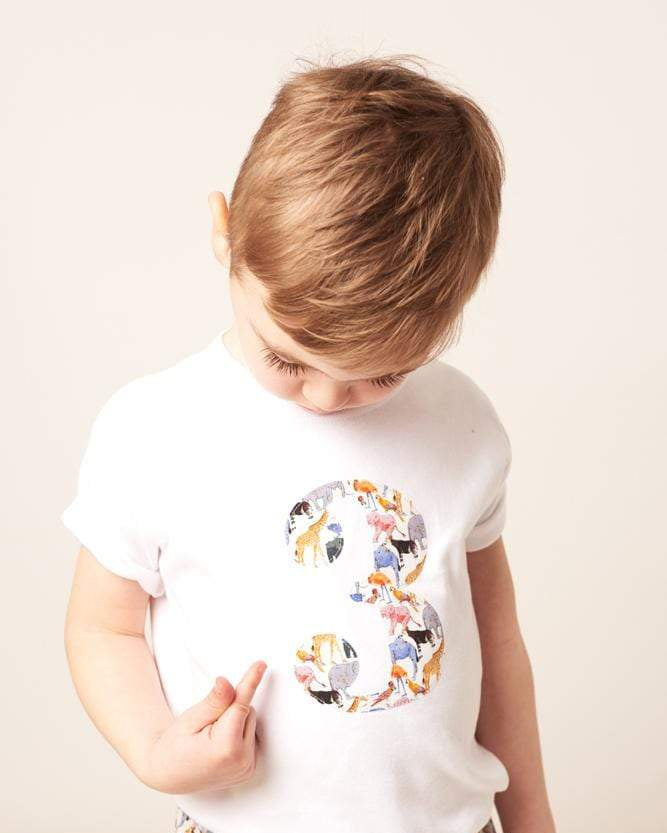 A three year old on their first birthday wearing a white cotton t-shirt with a zoo animal number 3 on the front.