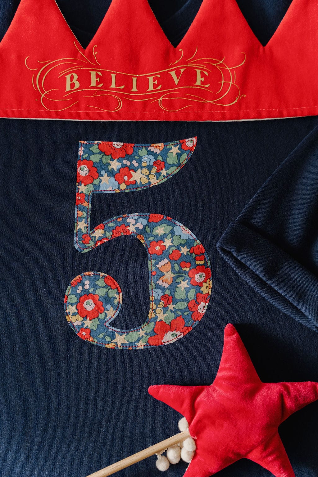 A navy t-shirt with a Liberty floral and star Betsy Star number 5 on the front. Styled with a red velvet crown and wand.