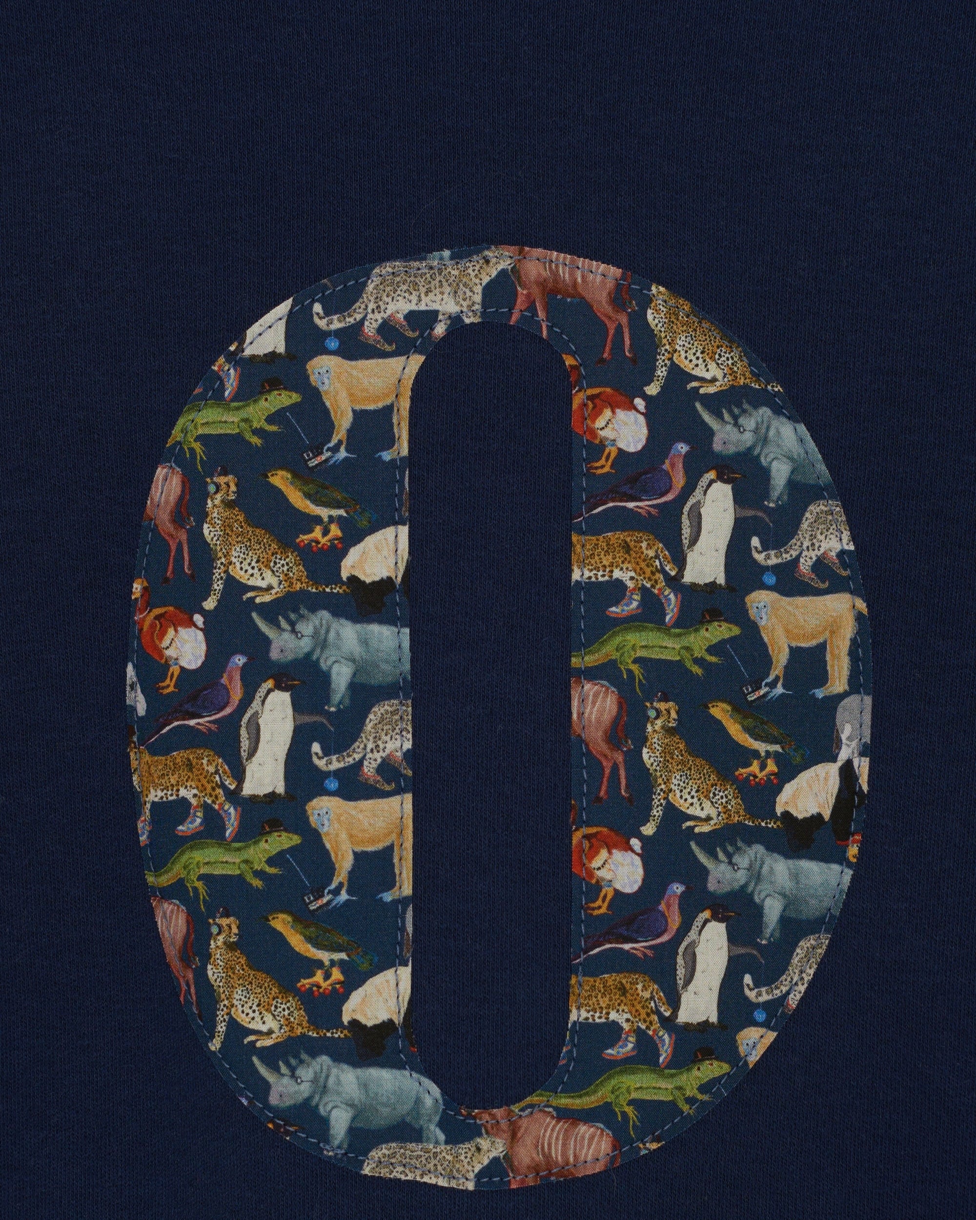 A close up of a personalised cotton navy long sleeve tee with an initial on the front made from Quey Zoo animal Liberty print fabric.