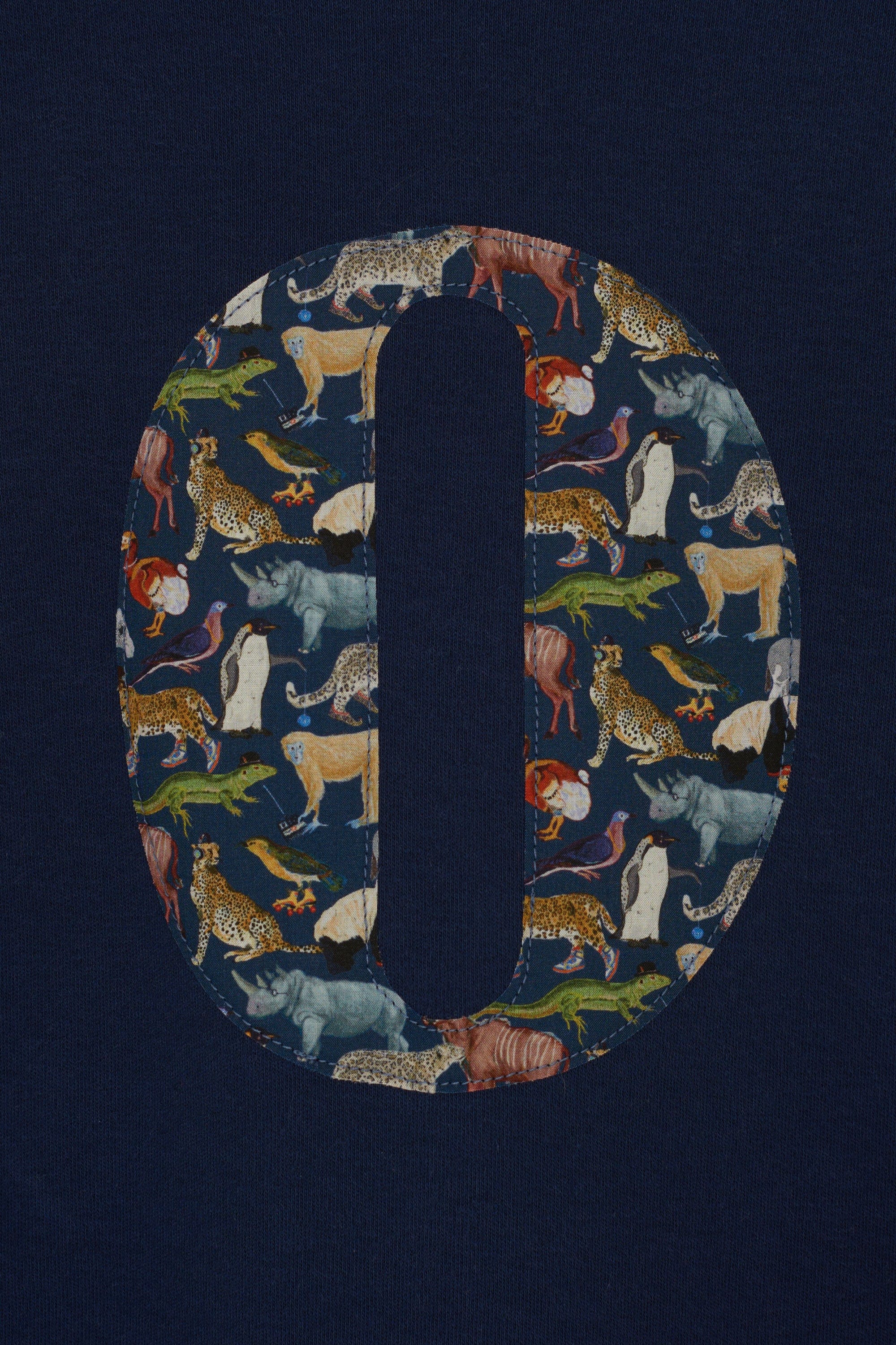 A close up of a personalised cotton navy long sleeve tee with an initial on the front made from Quey Zoo animal Liberty print fabric.