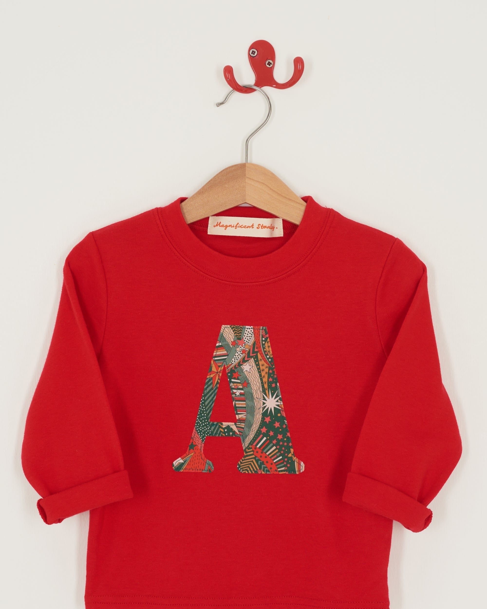 A close up of the appliqué on a personalised red cotton t-shirt with his initial in My Little Star Liberty print fabric.
