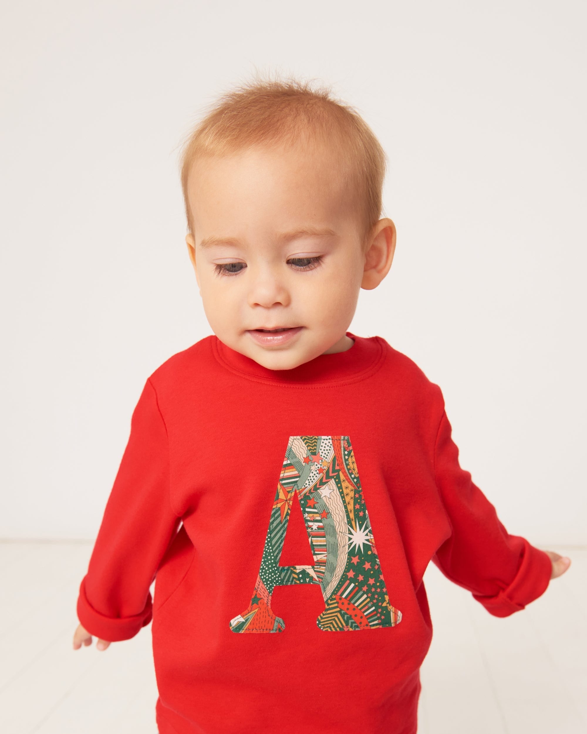 A one year old wearing a personalised red cotton t-shirt with his initial in My Little Star Liberty print fabric.