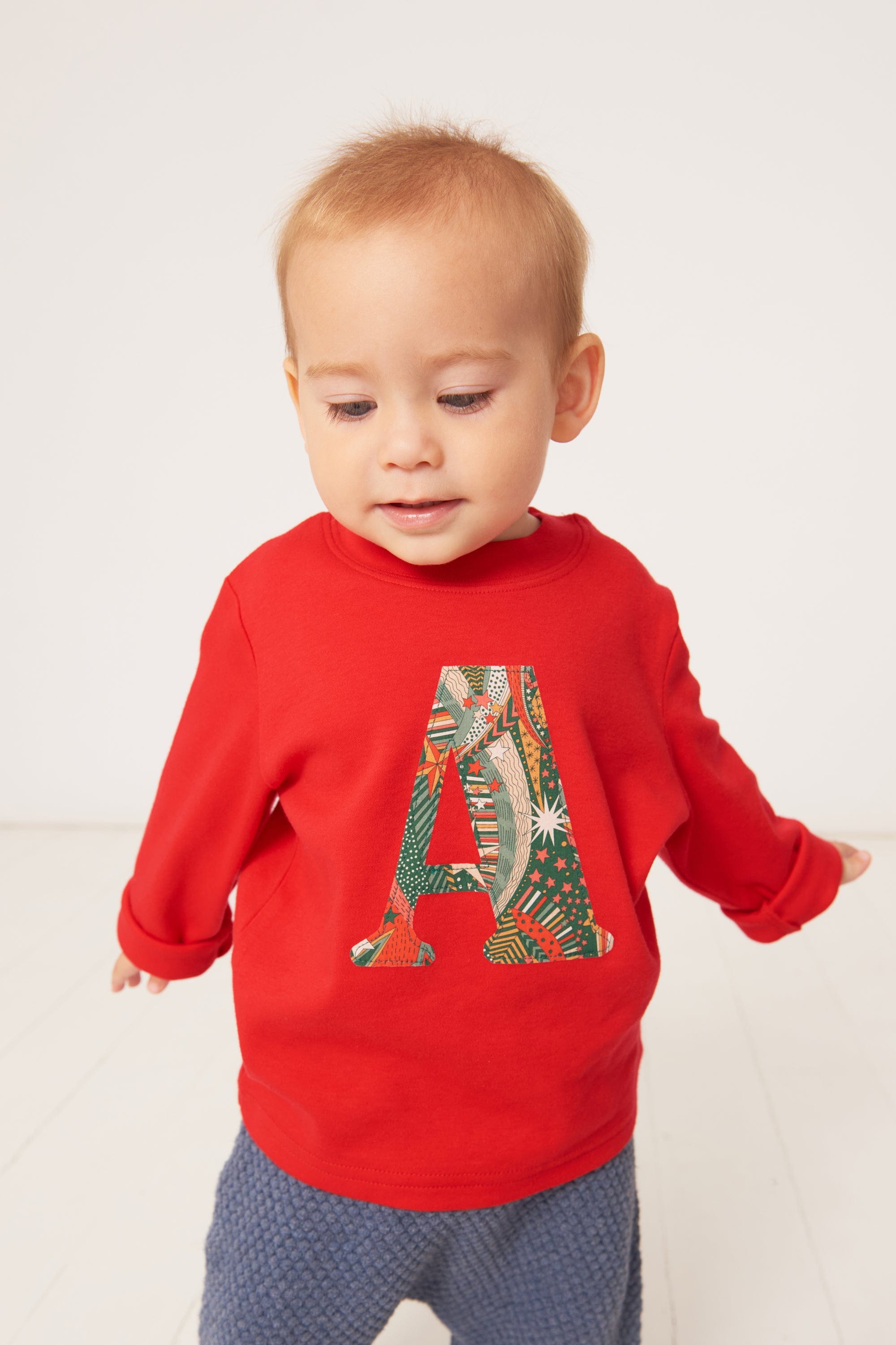 A one year old wearing a personalised red cotton t-shirt with his initial in My Little Star Liberty print fabric.
