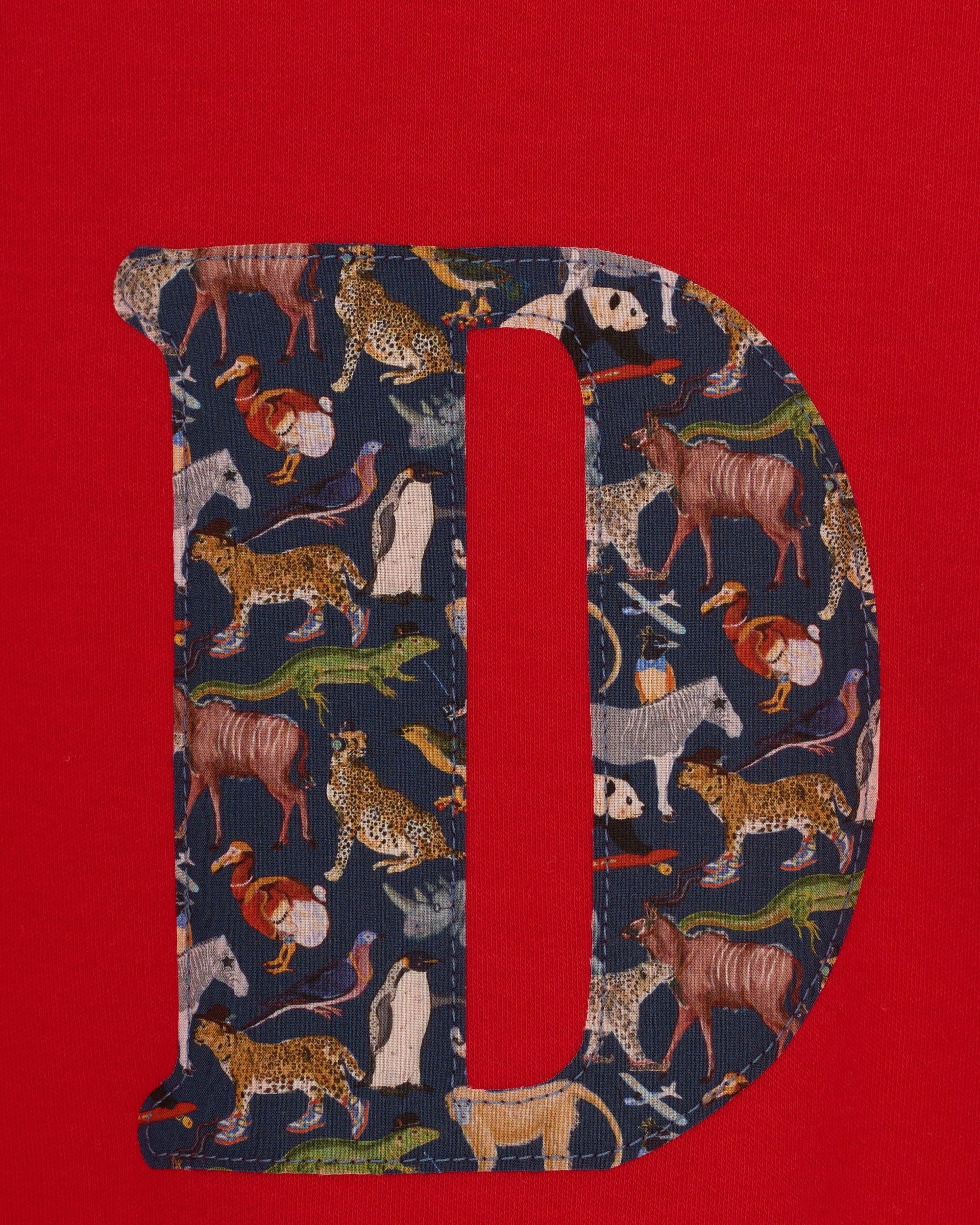 A personalised red cotton t-shirt with his initial on the front made out of a Liberty zoo animal print Quey 2.