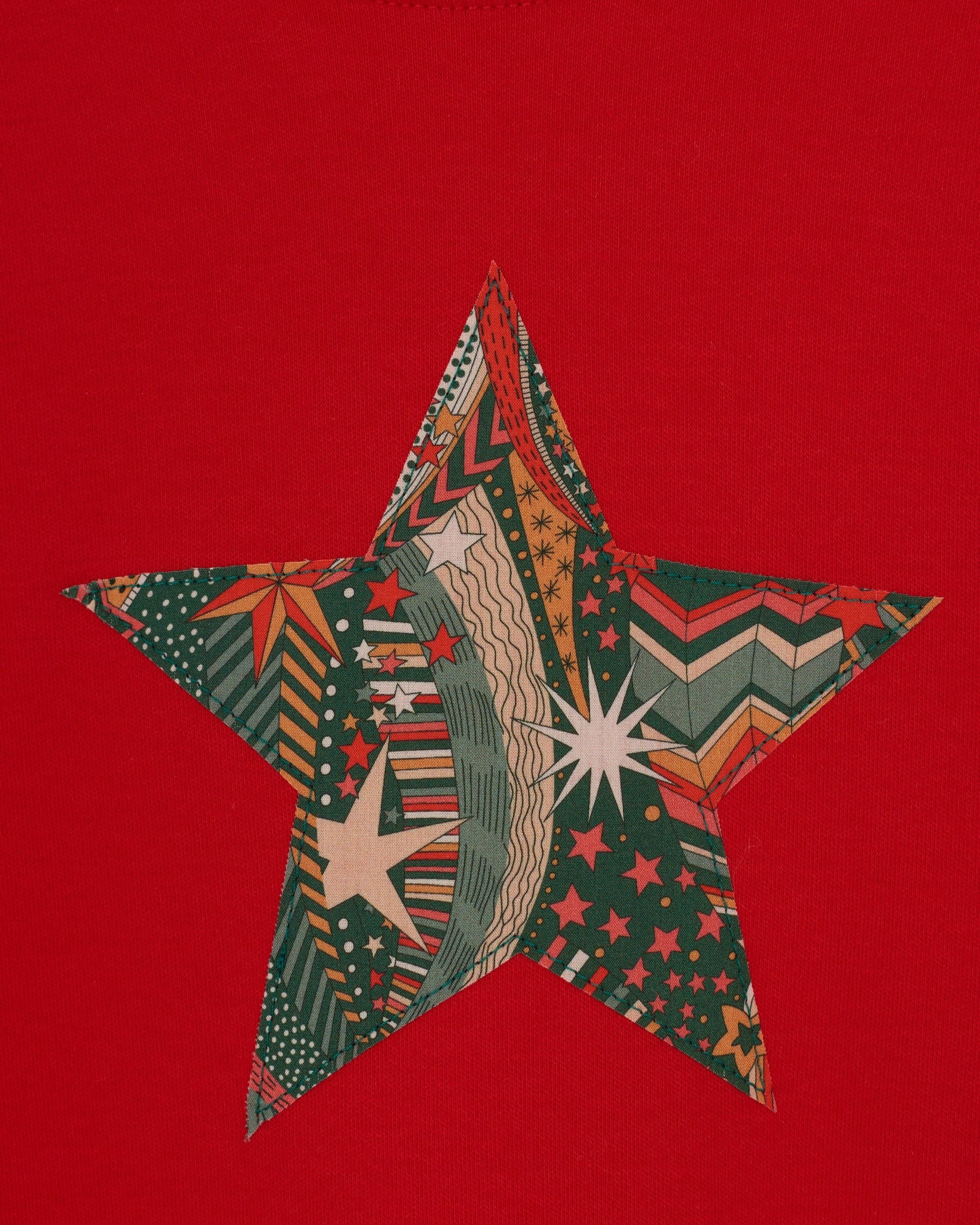 A red Christmas t-shirt with a festive star on the front in a starry Liberty print.