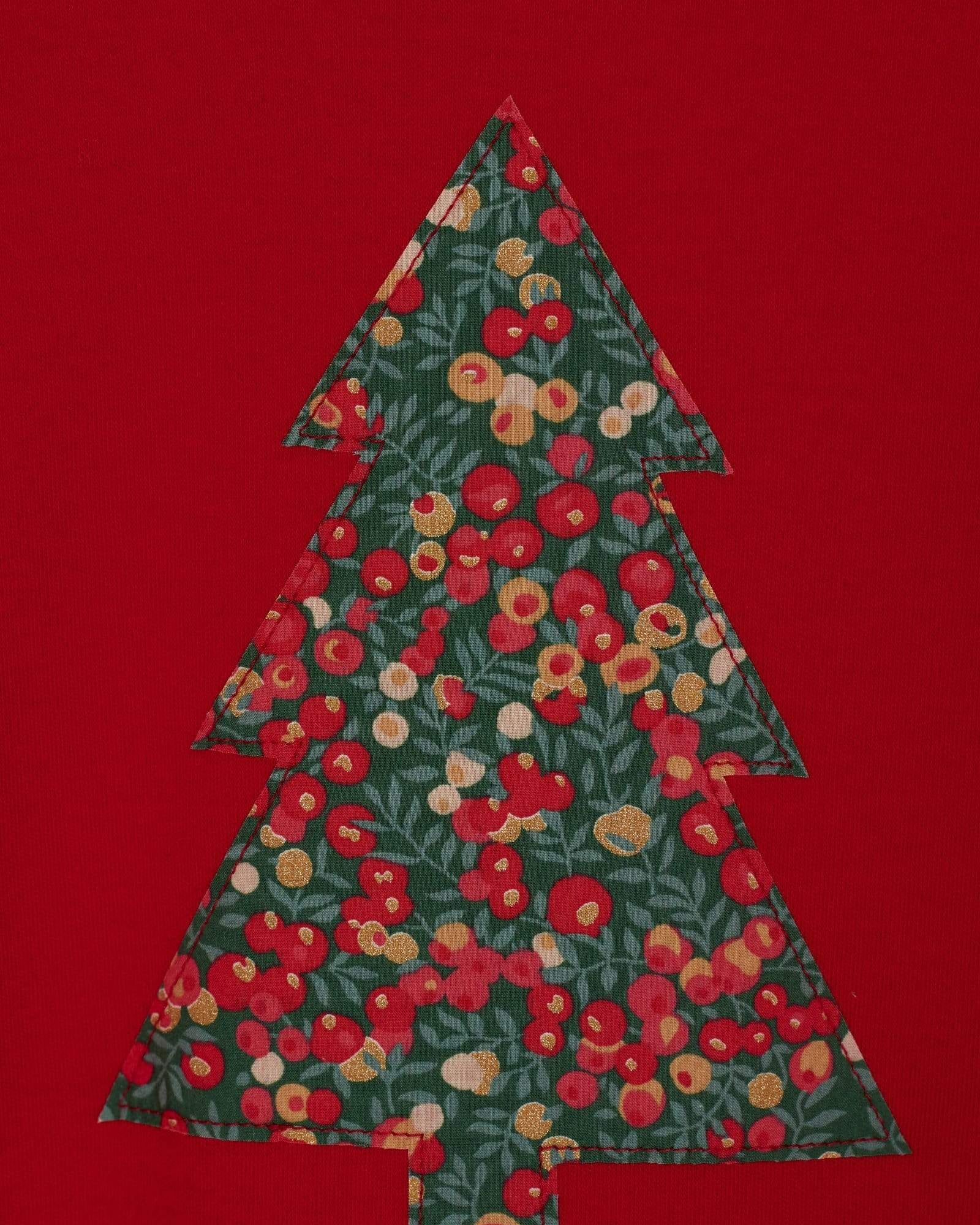 A close up of a festive red t-shirt with a Christmas tree on the front made from Liberty Glitter Wiltshire berry fabric.