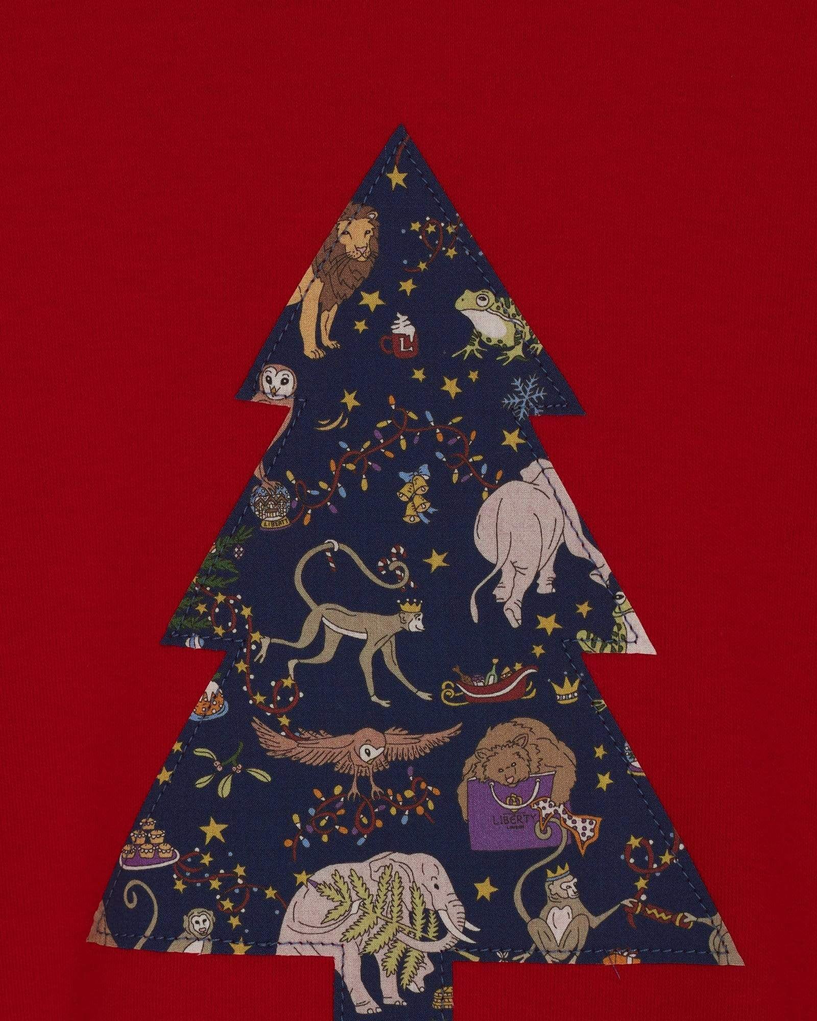 A close up of the appliqué on a festive red t-shirt with a christmas tree on the front made from Liberty Christmas fabric.