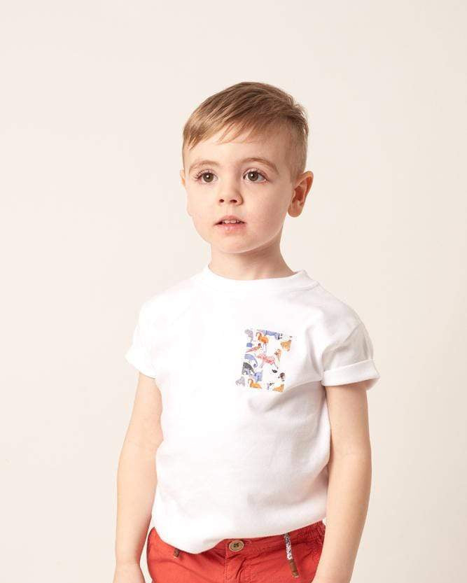 Child wearing a white t-shirt with a small initial design on the front in zoo liberty print on the back.
