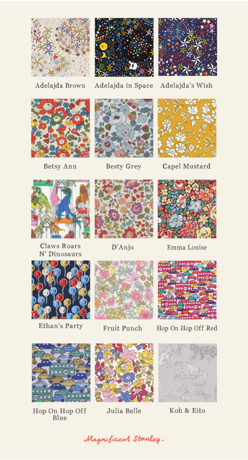 A grid of 24 liberty print fabric swatches with colourful patterns and names underneath, including Adelajda Brown, Besty Ann, Capel Mustard, and others, on a light beige background. The brand name 'Magnificent Stanley' appears at the bottom. Patterns feature cars, planes, flowers, balloons, dinosaurs, stars and cats.