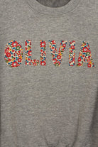a grey kids personalised sweatshirt with the name Olivia on it cut from Betsy Ann Liberty print.