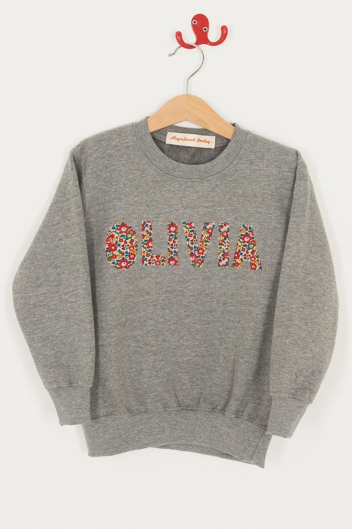 a grey kids personalised sweatshirt with her name on it cut from Betsy Ann Liberty print.
