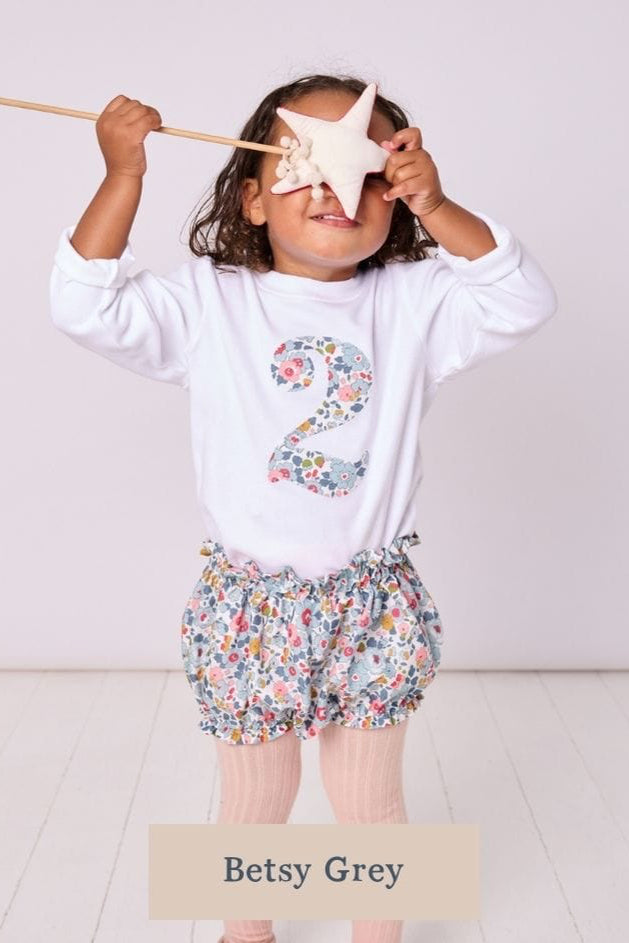 a 2 year old girl wearing a birthday kids white t-shirt with a number 2 cut from betsy grey liberty floral print on the front