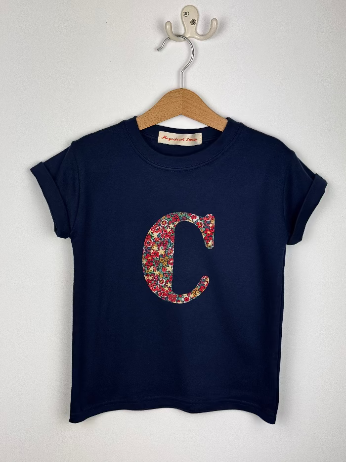 Navy blue t-shirt with floral letter 'C' on a hanger against a white background