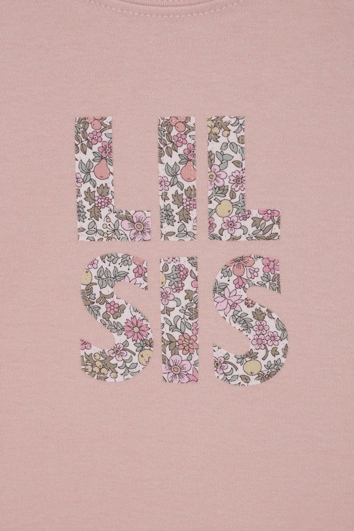 a pink little sister sibling t-shirt with the words Lil Sis on the front cut from floral Liberty print.