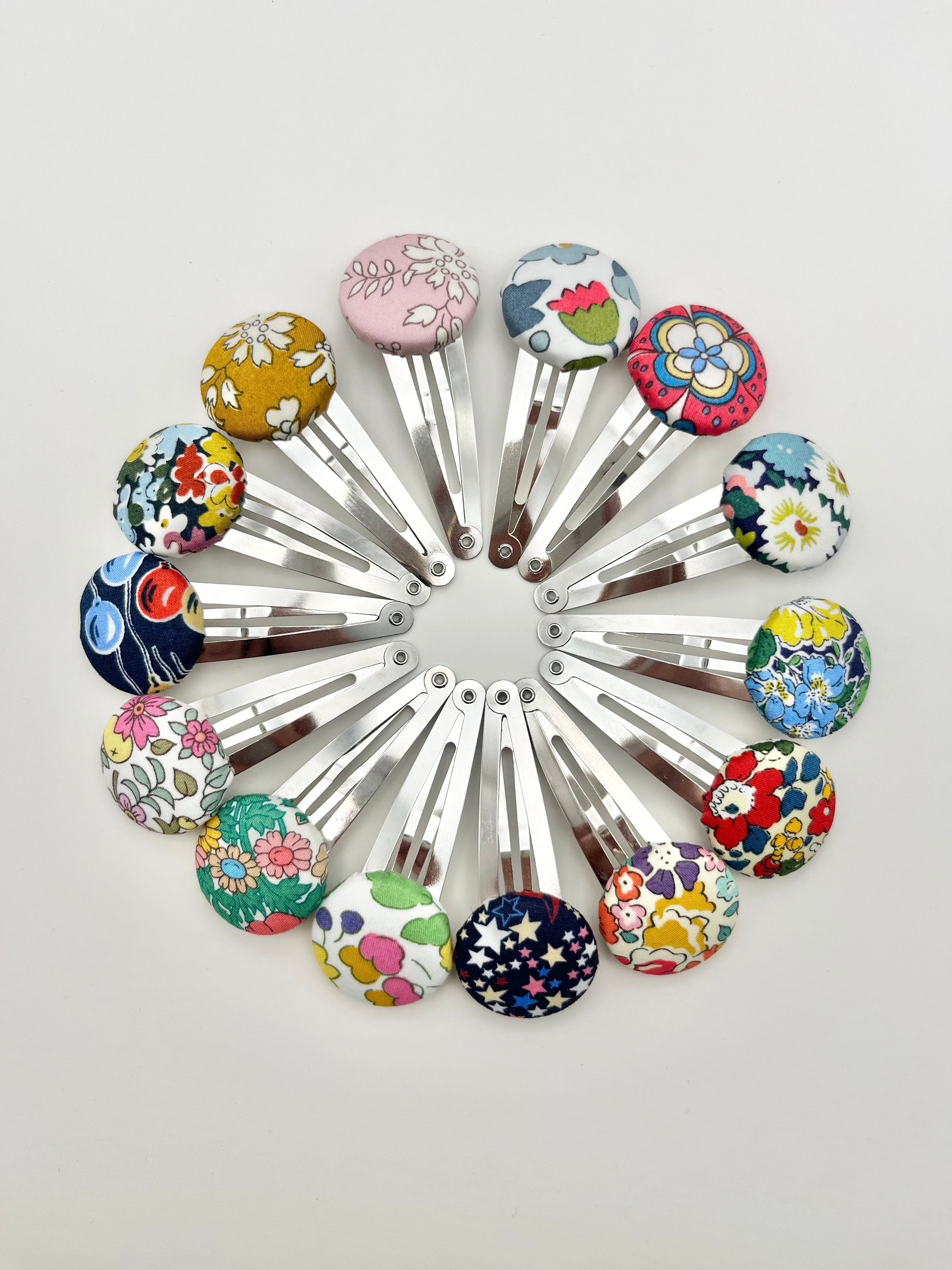 A collection of Liberty print hair bobble hair clips with various floral patterns in a circle formation.