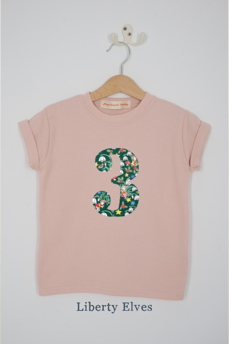 a pink 3rd birthday t-shirt with a number 3 cut from Liberty Elves festive Liberty print  featuring Elves, snowdrops, holly and stars on the front