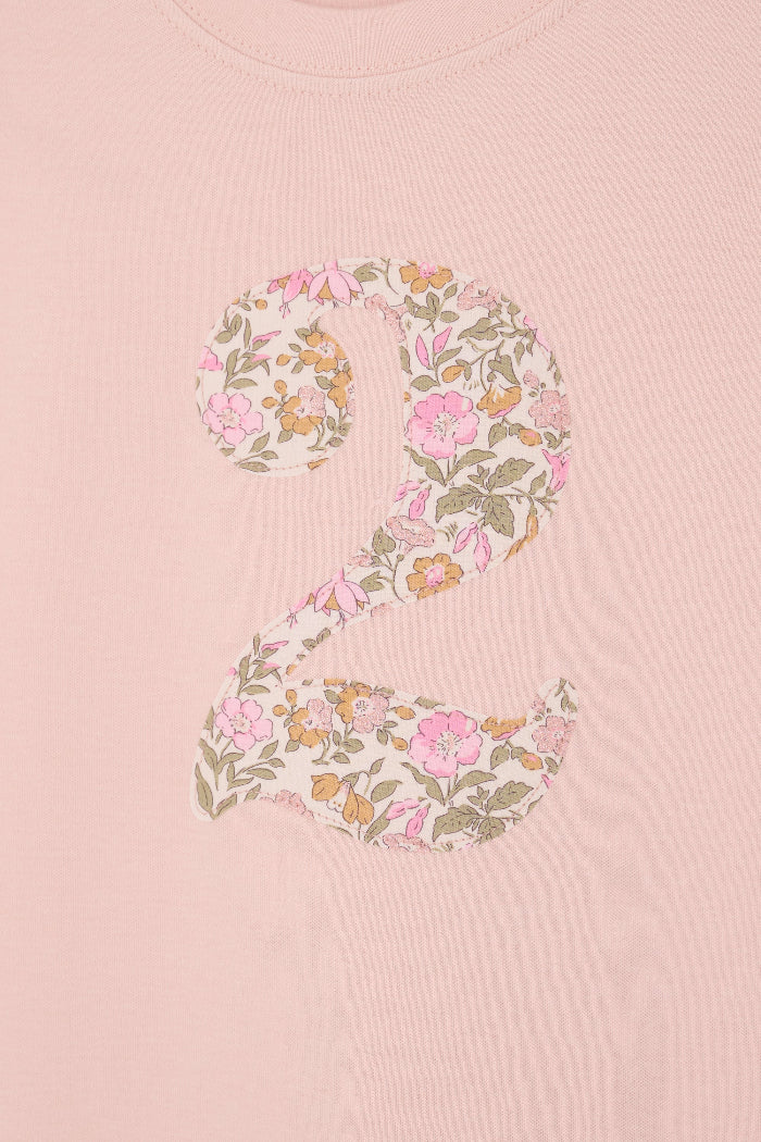 a 2 year old birthday girl wearing a pale pink t-shirt with the number 2 sewn on the front cut from liberty floral Mamie print.