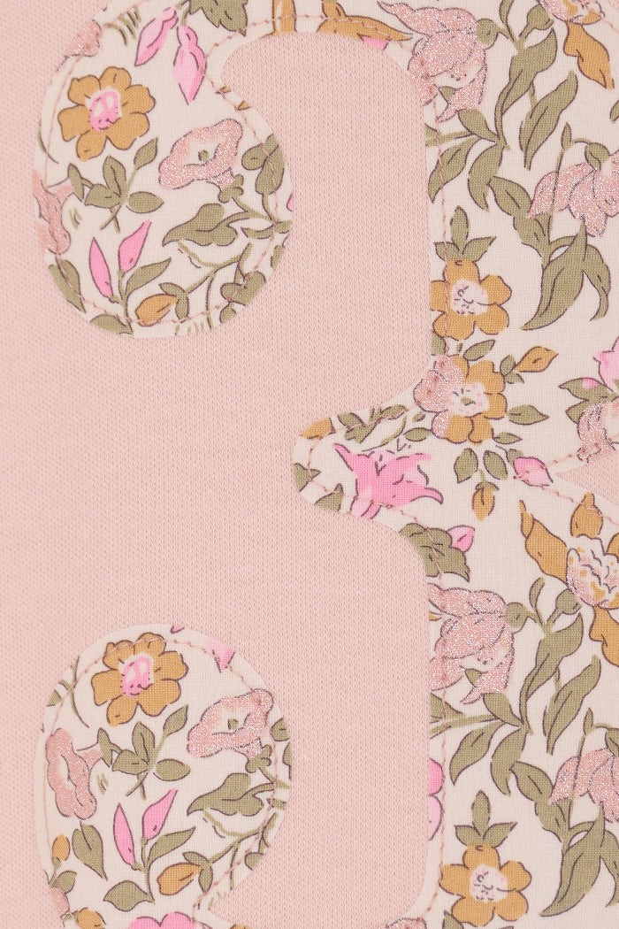 a pale pink t-shirt with the number 3 sewn on the front cut from liberty floral Mamie print. a close up of the applique stitching