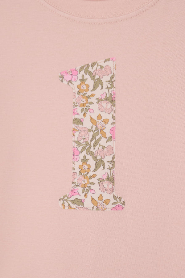 A pale pink t-shirt with the number 1 sewn on the front cut from liberty floral Mamie print. This shows a close up of the applique stitching