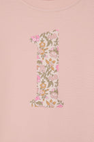 A pale pink t-shirt with the number 1 sewn on the front cut from liberty floral Mamie print. This shows a close up of the applique stitching