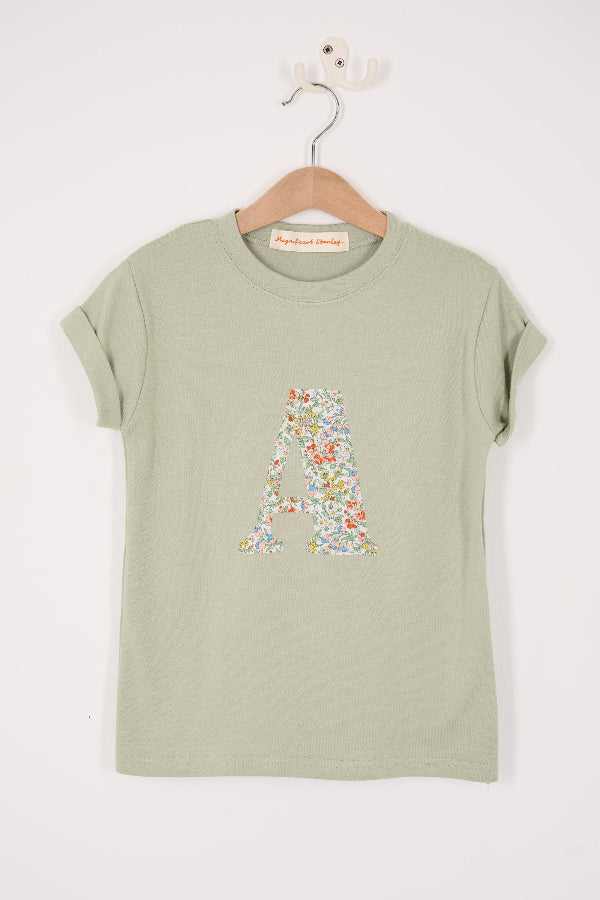 A personalised kids sage green t-shirt with his initial cut from nazanin liberty print on the front.