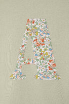 A personalised kids sage green t-shirt with his initial cut from Nazanin liberty print on the front.