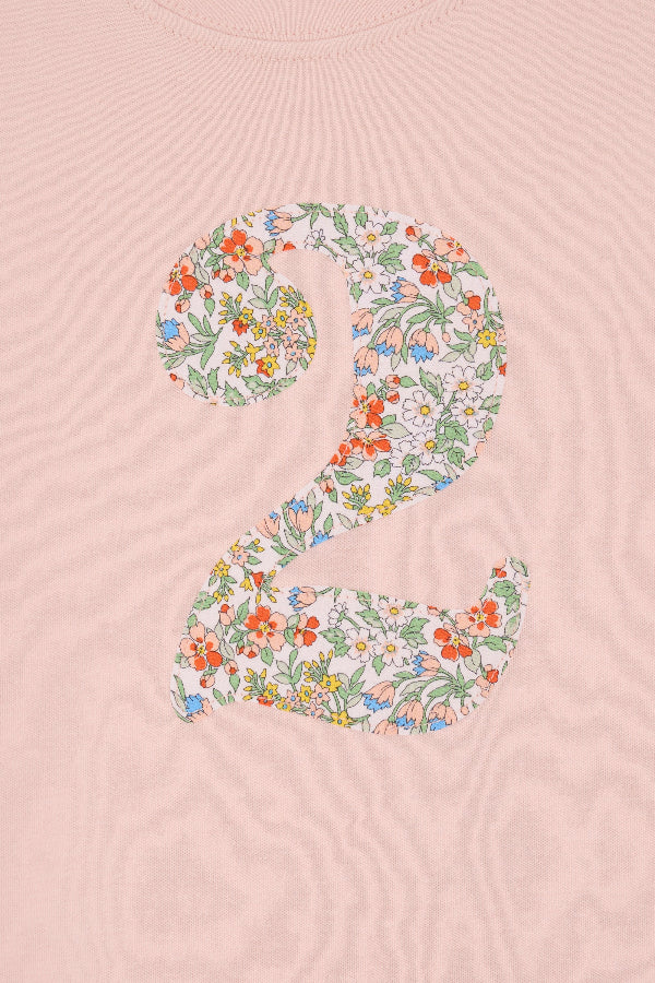 A Pink t-shirt with a Liberty Nazanin floral number '2', a close up of the stitching