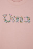A soft pink kids t-shirt with a name cut from Liberty print in lowercase letters.