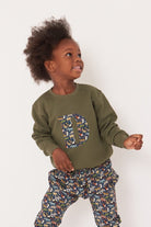 A 3 year old boy wearing a personalised  khaki sweatshirt with an initial made from quey 2 Liberty animal print fabric.