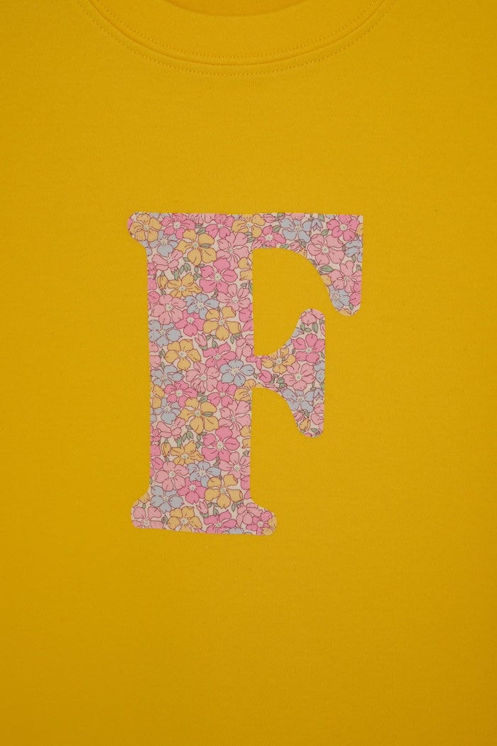 a personalised kids yellow t-shirt with an initial cut from sadie rose liberty floral print on the front