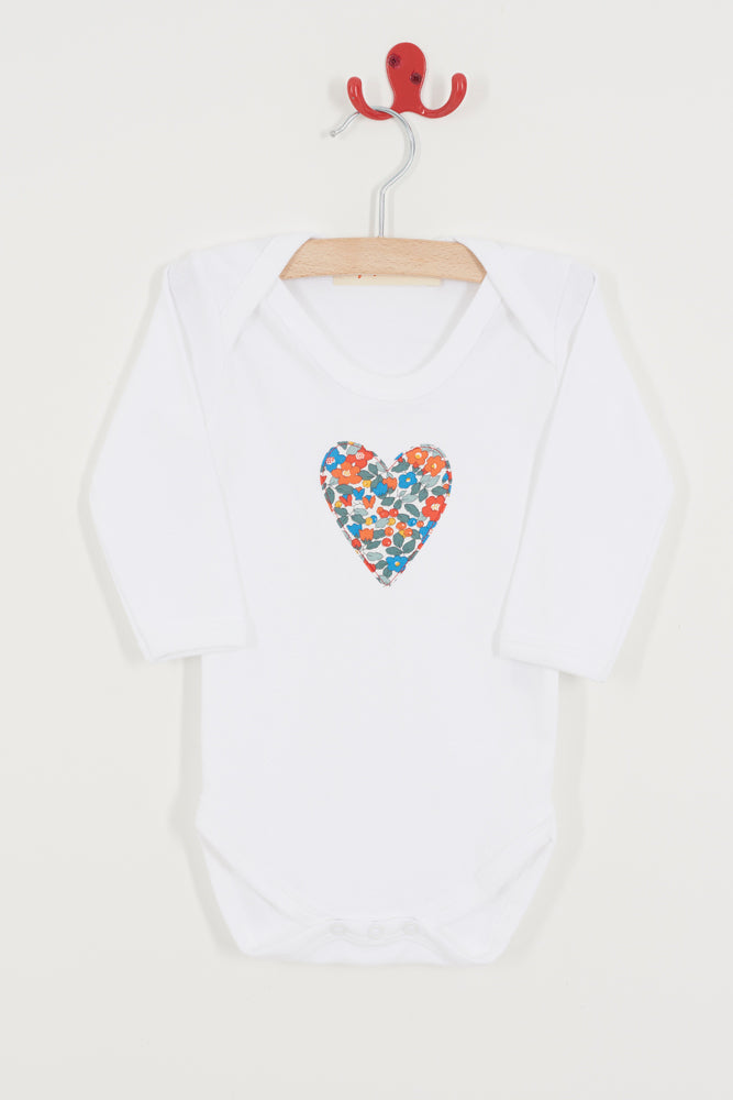 White baby onesie with a colourful heart design on a hanger against a white background