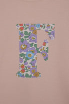 a close up of the appliqué stitching on a personalised kids blush pink  t-shirt with an initial cut from Betsy Purple liberty floral print on the front.