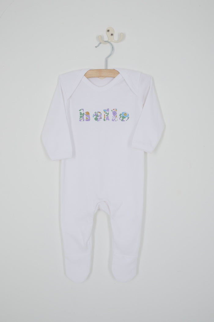 A white cotton baby bodysuit with the word hello made from Betsy Liberty Print sewn onto the front.