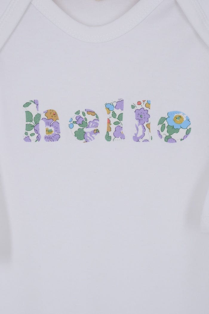 Close up of a white cotton romper with the word hello on it. the letters are cut from Betsy Purple liberty print and appliquéd onto the romper.