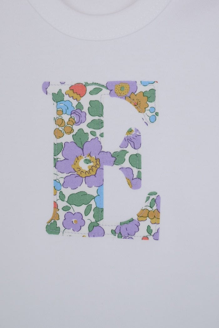 a personalised bodysuit baby grow with an initial cut from floral betsy purple Liberty print, a close up of the appliqué stitching 