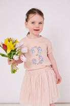 a 3 year old girl wearing a pink birthday t-shirt with a number 3 cut from betsy purple liberty floral print on the front