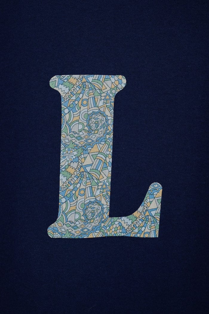 a personalised kids navy t-shirt with an letter cut from brave noah dragons print on the front, a close up of the appliqué stitching.